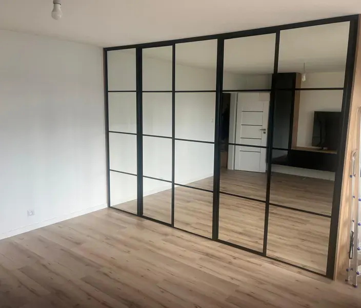 Ścianka działowa w stylu loft — czarne profile, tafle szkła i lustra dzielące pokój