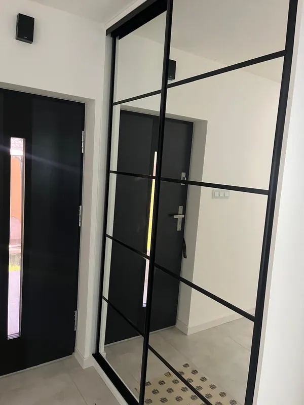 Lustrzana szafa przesuwna w przedpokoju, czarne profile w stylu loft